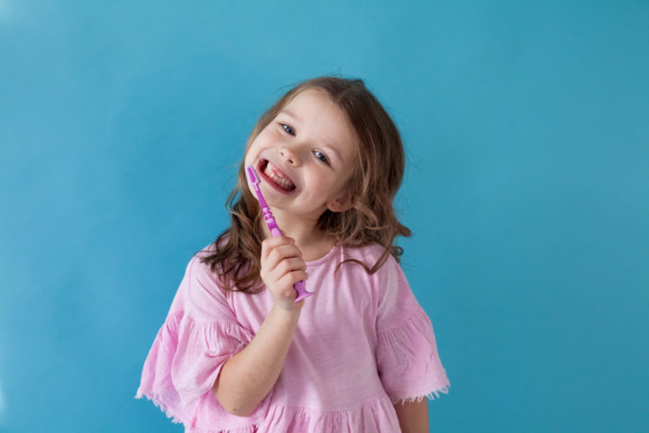 Smiling little girl brushing her teeth at Yukon Kids Dental